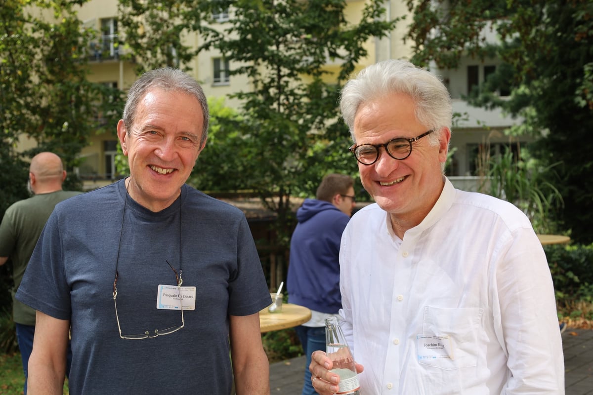 Pasquale Di Cesare und Joachim Krug lächeln im Innenhof.